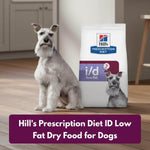 Load image into Gallery viewer, Dog sitting next to a bag of Hill's Prescription Diet ID Low Fat Dry Food for Dogs on a wooden floor.