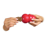 Load image into Gallery viewer, Red KONG dog toy with a small treat held between two hands on a white background
