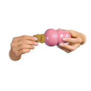 Pink KONG dog toy with a treat held by a hand on a white background